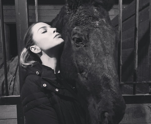 Lauren German with a horse in the stable.
